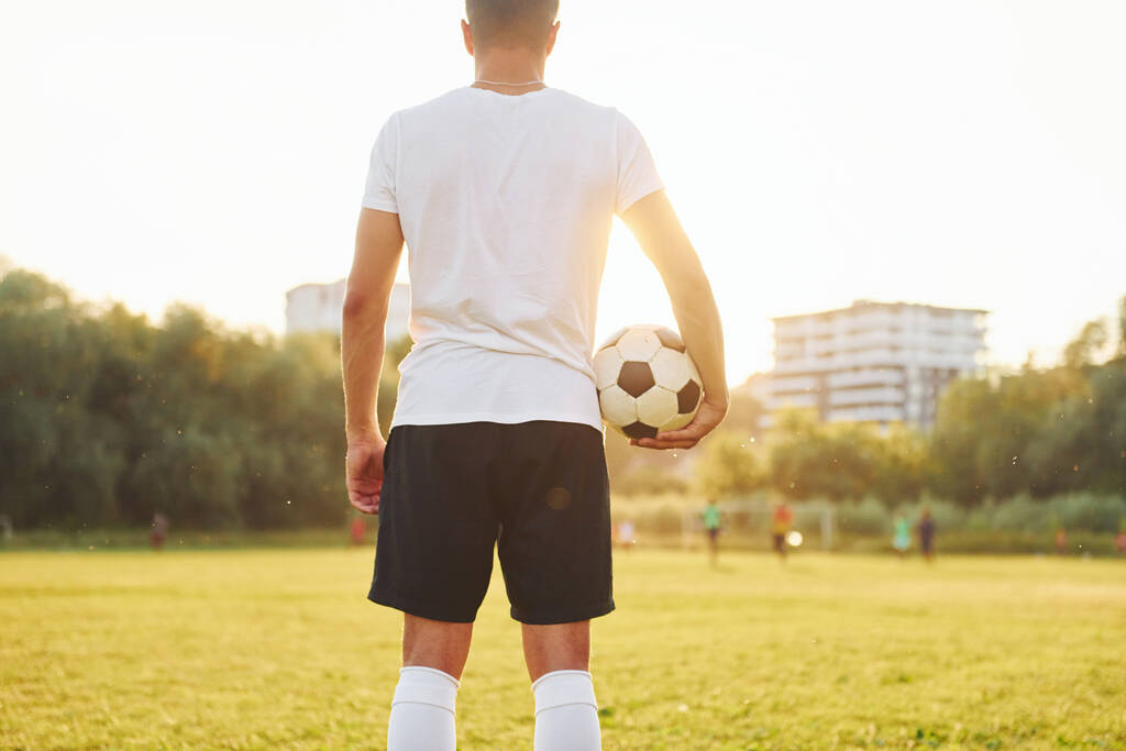 Debout et tenant la balle dans la main. Un jeune footballeur s'entraîne sur le terrain de sport. - Photo, image