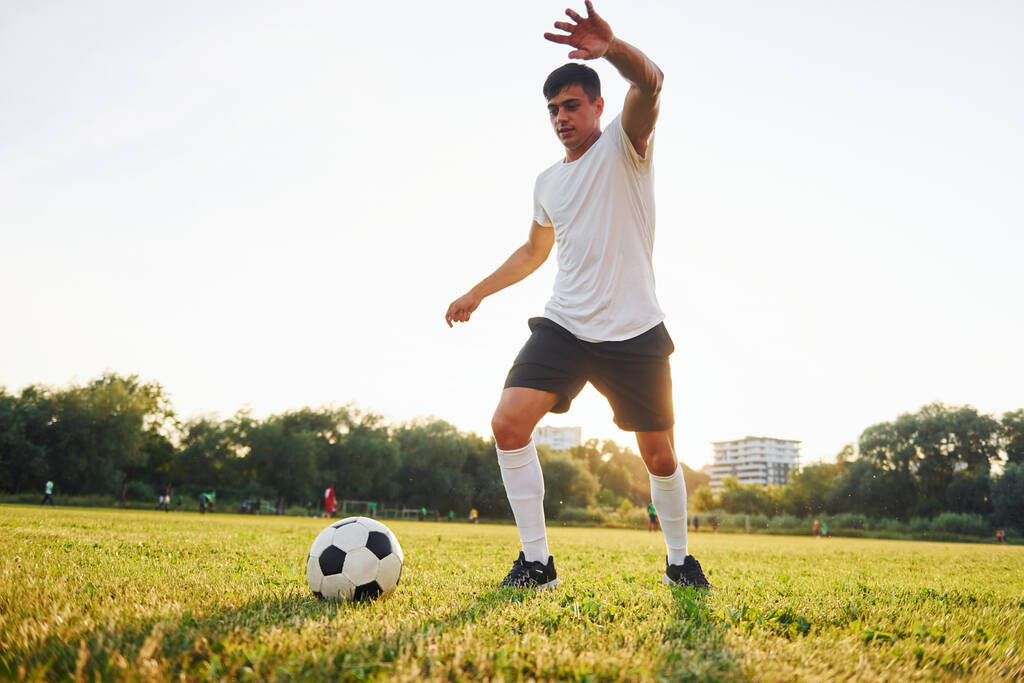 Aktive Aktivitäten am Wochenende. Wald im Hintergrund. Junge Fußballer trainieren auf dem Sportplatz. - Foto, Bild