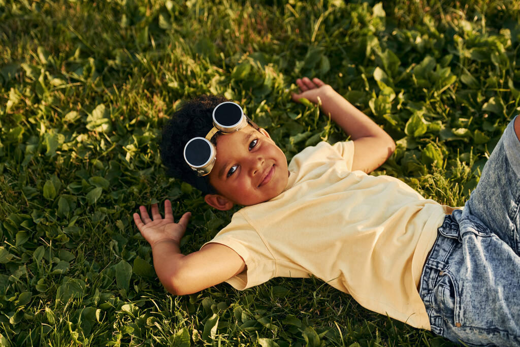 Liegen auf dem Gras. Afroamerikanische Kinder haben im Sommer tagsüber Spaß auf dem Feld. - Foto, Bild