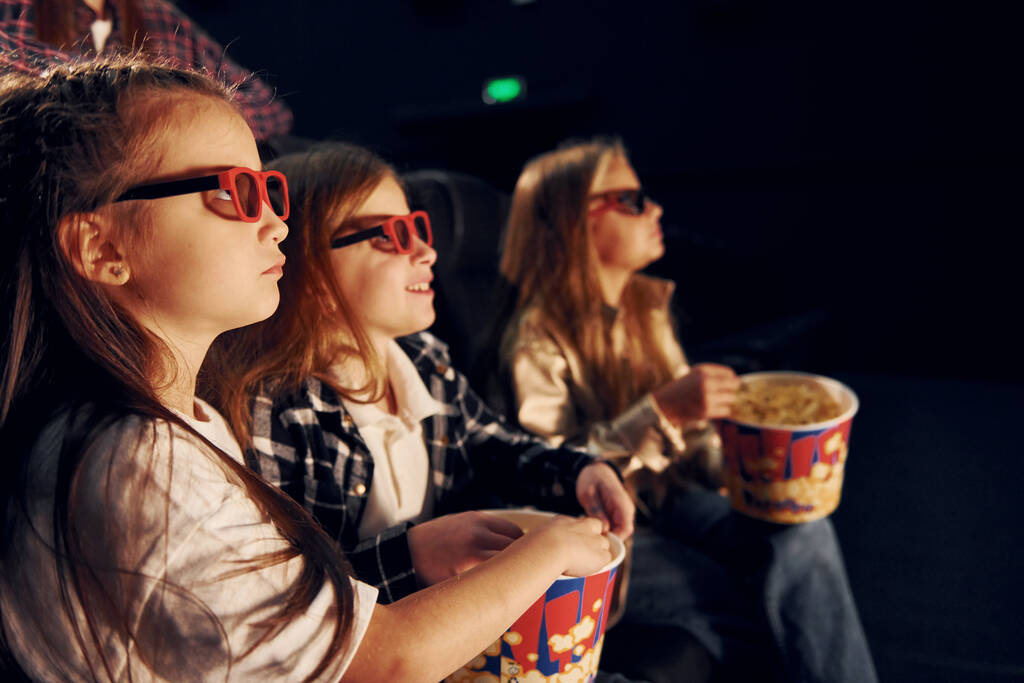 Їж попкорн. Група дітей, які сидять у кіно і переглядають фільм разом
. - Фото, зображення