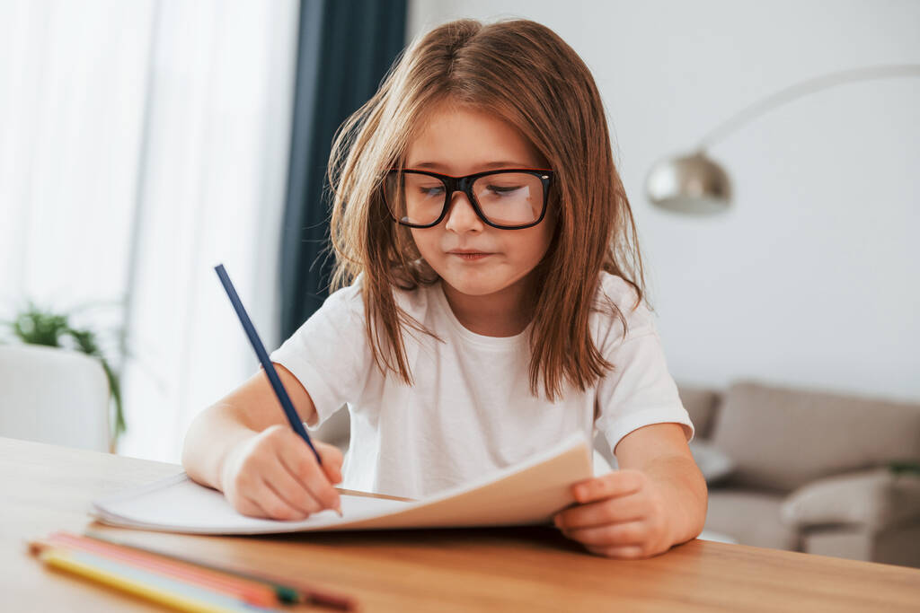 Kleines Mädchen sitzt am Tisch und lernt zeichnen. - Foto, Bild