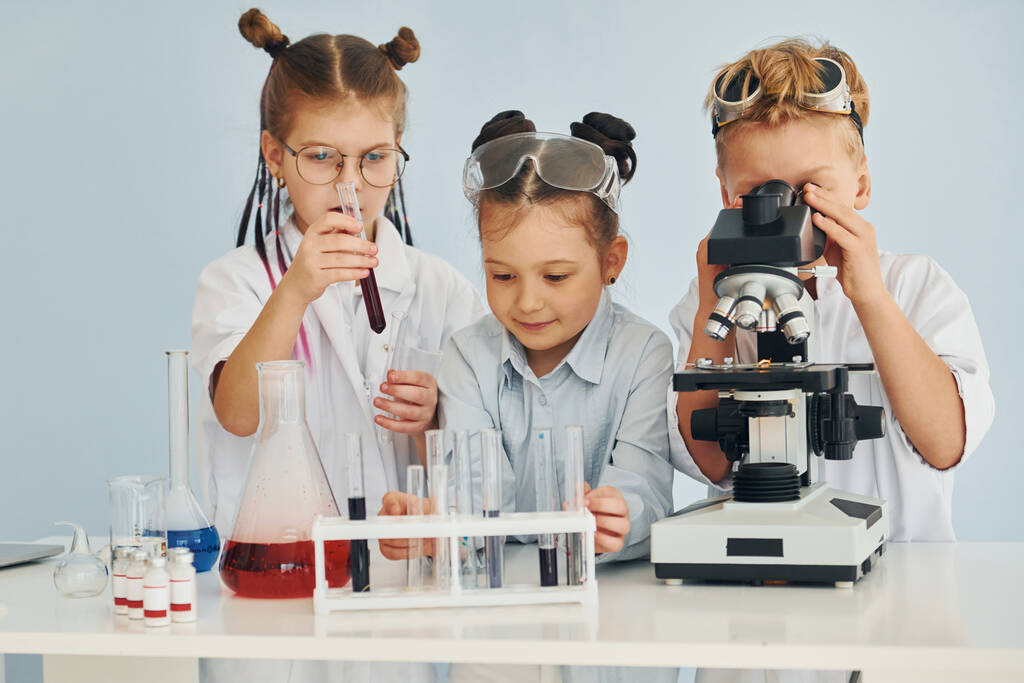 Koeputket värikkäitä nesteitä. Valkotakkiset lapset esittävät tutkijaa laboratoriossa laitteiden avulla. - Valokuva, kuva