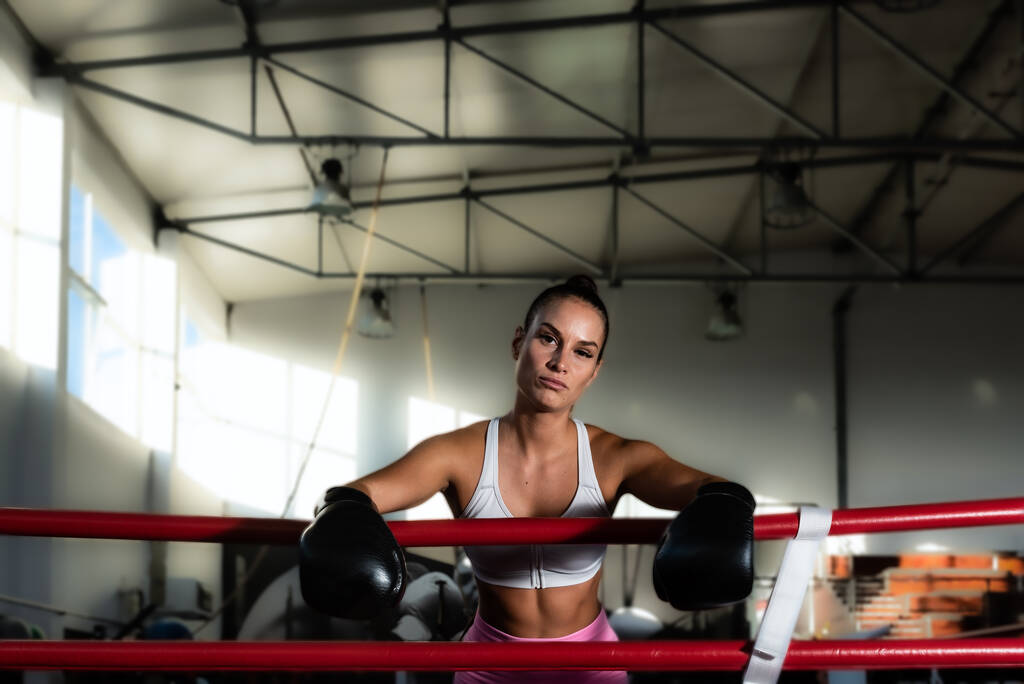 Jonge zweterige bokser vrouw of meisje in de boksring toekomstige kampioen oefenbox boor met bokshandschoenen aan haar handen. Sportieve aantrekkelijke vechter vrouwelijke training voor gevecht match. - Foto, afbeelding
