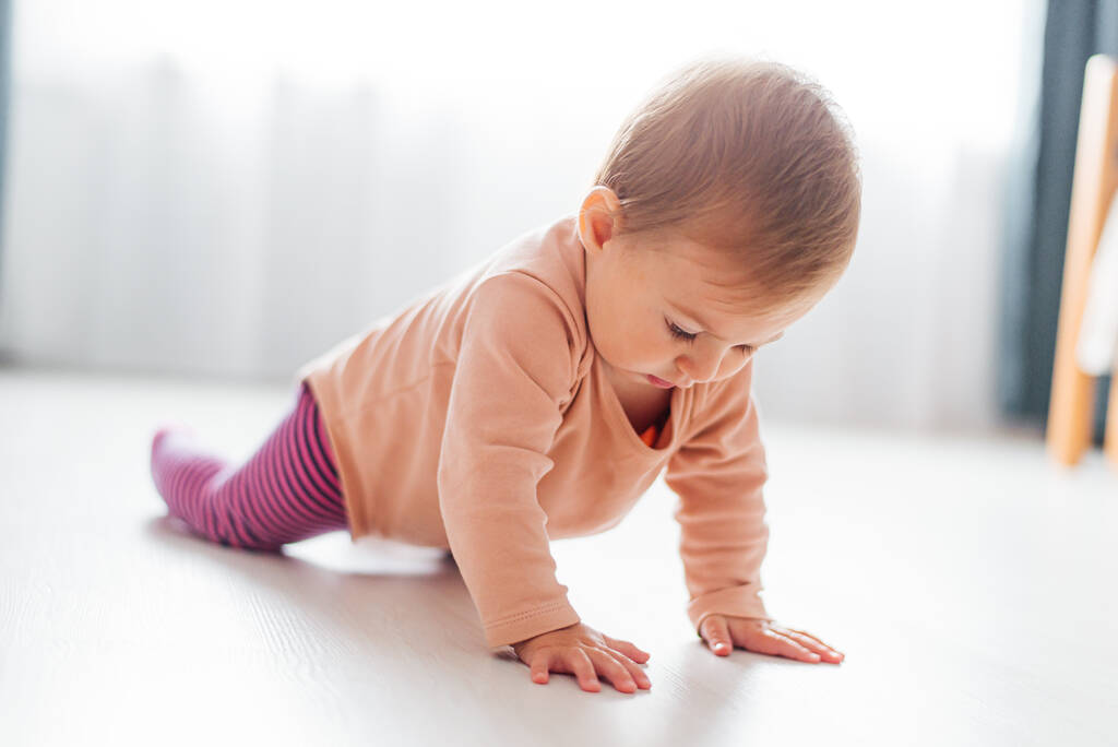 A girl child learns to crawl the floor. First steps - Photo, Image