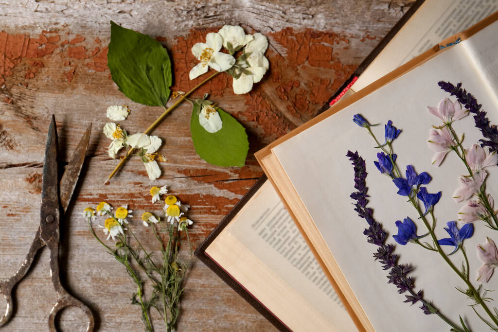 Oude schaar met mooie gedroogde bloemen en boeken op houten tafel, plat gelegd - Foto, afbeelding