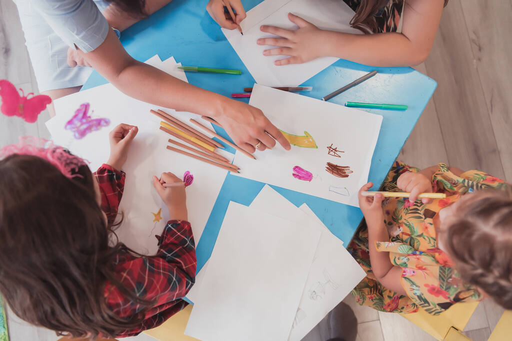 Kreatywne dzieci podczas zajęć plastycznych w przedszkolu lub szkole podstawowej rysunek z nauczycielką.  - Zdjęcie, obraz