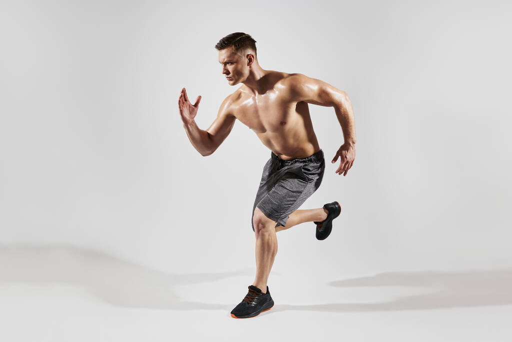 Hombre musculoso guapo con torso perfecto que corre sobre fondo blanco - Foto, Imagen