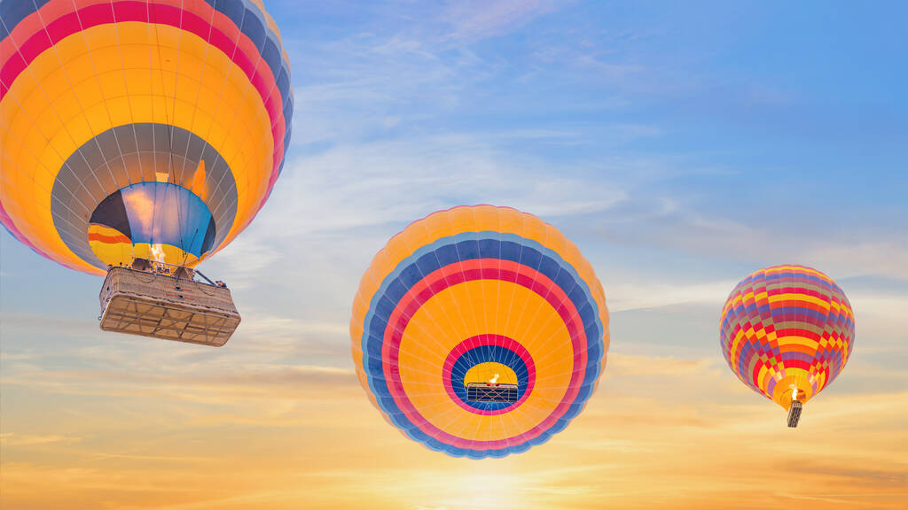 pohled zdola na vícebarevný horkovzdušný balón stoupající až k obloze v ranních hodinách východu slunce - Fotografie, Obrázek