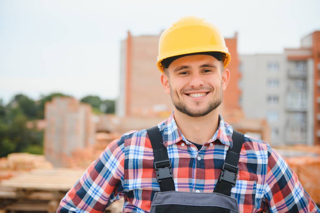 Keltainen kypärä. Nuori mies, joka työskentelee rakennuspuvussa päivällä - Valokuva, kuva
