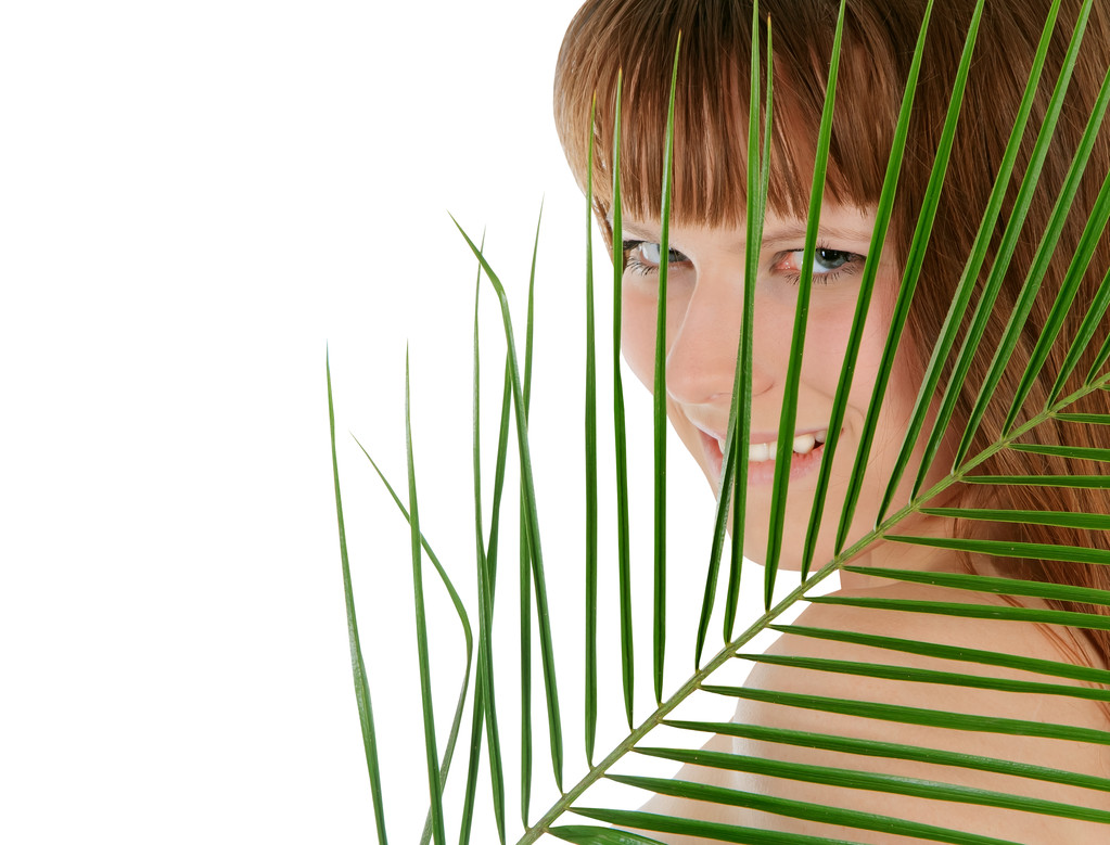 Bastante hembra detrás de hoja de palma sobre blanco
 - Foto, imagen