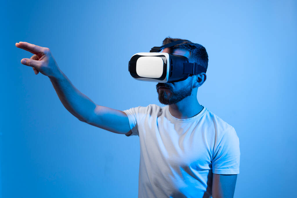 Fiatal szakállas férfi visel virtuális valóság szemüveg és videojátékok - Fotó, kép