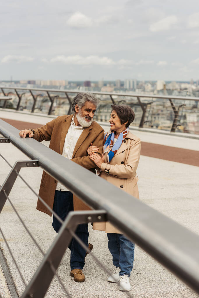 heureux senior femme étreignant mari barbu près de pont garde rail  - Photo, image