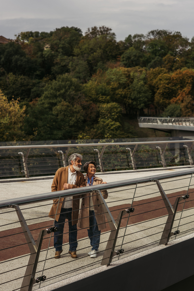 pełna długość szczęśliwy starszy kobieta i brodaty mężczyzna stojący w pobliżu mostu straży poręczy  - Zdjęcie, obraz