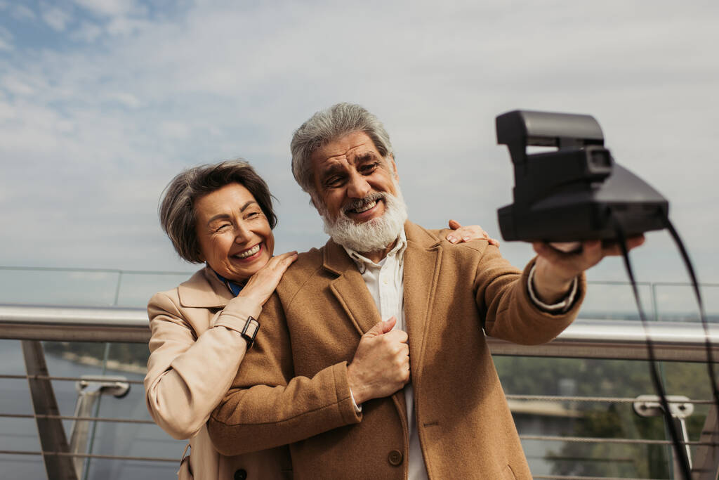 ευτυχισμένος ηλικιωμένος άνδρας που παίρνει selfie με χαρούμενη σύζυγο σε vintage κάμερα - Φωτογραφία, εικόνα