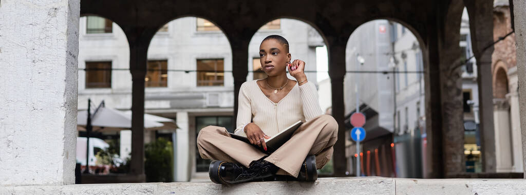 Trendy rövid hajú afro-amerikai nő kezében notebook szabadban Treviso, banner - Fotó, kép