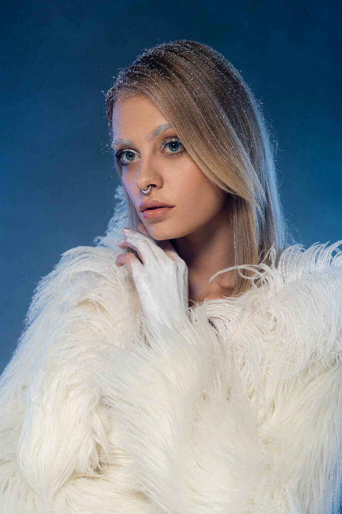 Saçları karlı, kışın koyu mavi makyajlı genç bir kadın.  - Fotoğraf, Görsel
