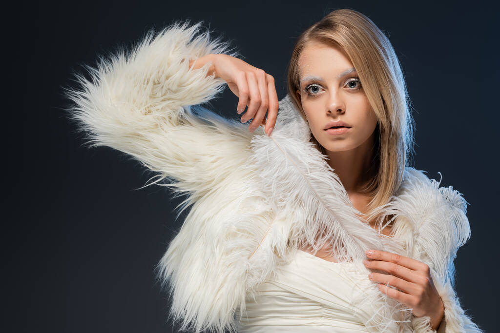 blondi nainen faux turkis takki poseeraa valkoinen sulka eristetty sininen - Valokuva, kuva