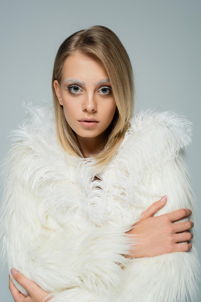 nuori malli valkoinen faux turkis takki höyhenet katselee kameraa poseeratessaan eristetty harmaa - Valokuva, kuva