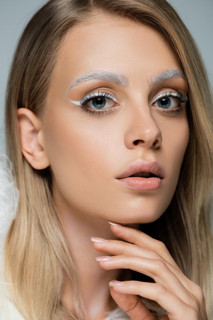 close up view of young model with winter makeup and frozen white eyebrows isolated on grey - Photo, Image