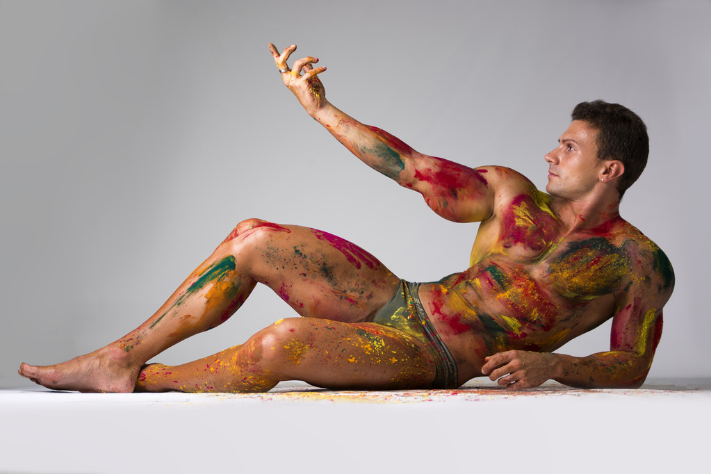 Gespierde jonge man met huid geschilderd met Holi kleuren, vaststelling van op de verdieping - Foto, afbeelding