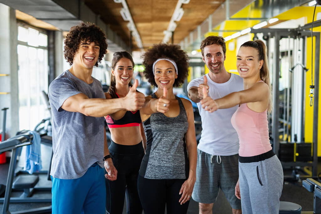 Een groep sportieve fitte mensen die trainen in een sportschool. Multiraciale vrienden die samen trainen in een fitnessclub. - Foto, afbeelding