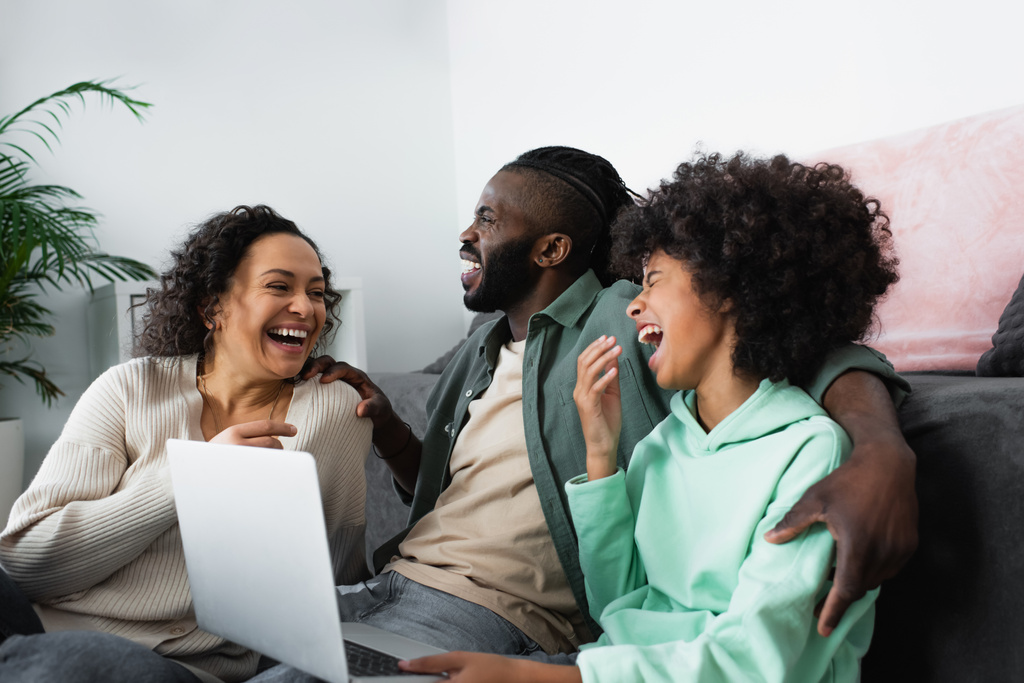 wesoła afrykańska rodzina śmieje się i ogląda film na laptopie w domu - Zdjęcie, obraz