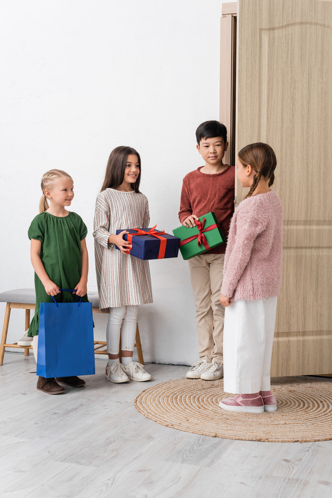 Веселые межрасовые дети с подарками у друзей и у дверей дома  - Фото, изображение