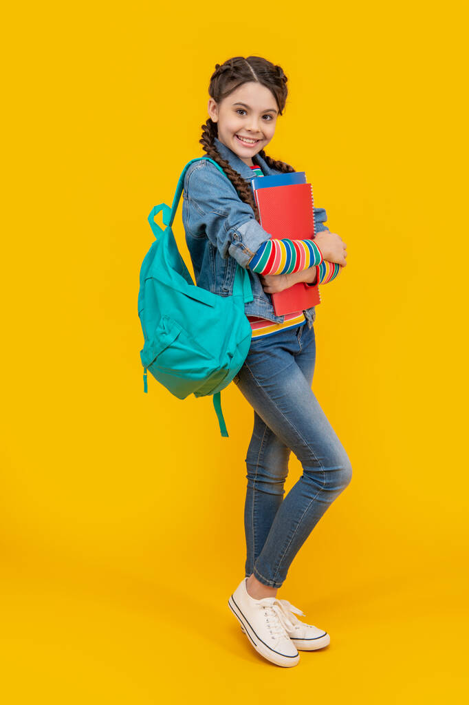 Boldog kamasz iskolás lány sárga háttér. Kamasz lány vissza az iskolába. Kamasz tanulók könyveivel. Szeptember 1. Tudásnap. - Fotó, kép