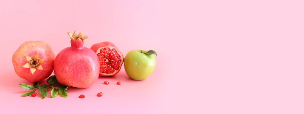 Rosz hashanah (żydowskie wakacje noworoczne) koncepcja. Granat i jabłko tradycyjne symbole na różowym tle - Zdjęcie, obraz