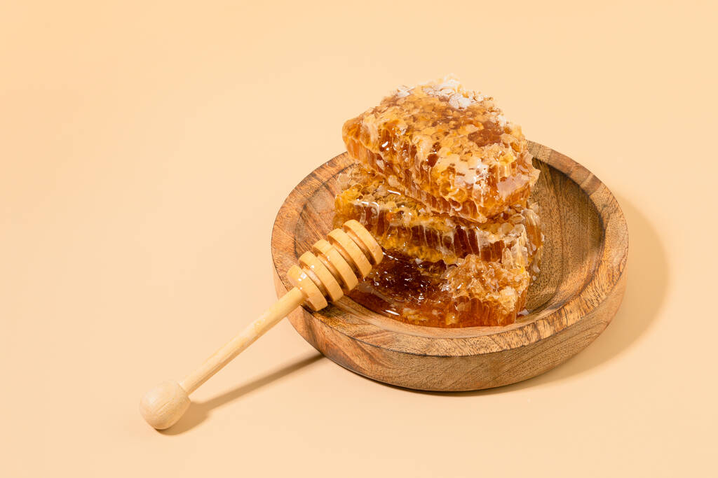 honing en honing dipper stok in een houten kom - Foto, afbeelding