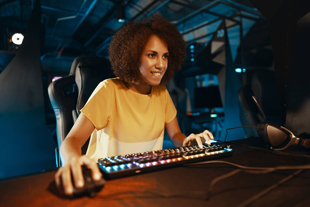 Joven mujer rizada jugando juegos cibernéticos. Foto de alta calidad - Foto, Imagen