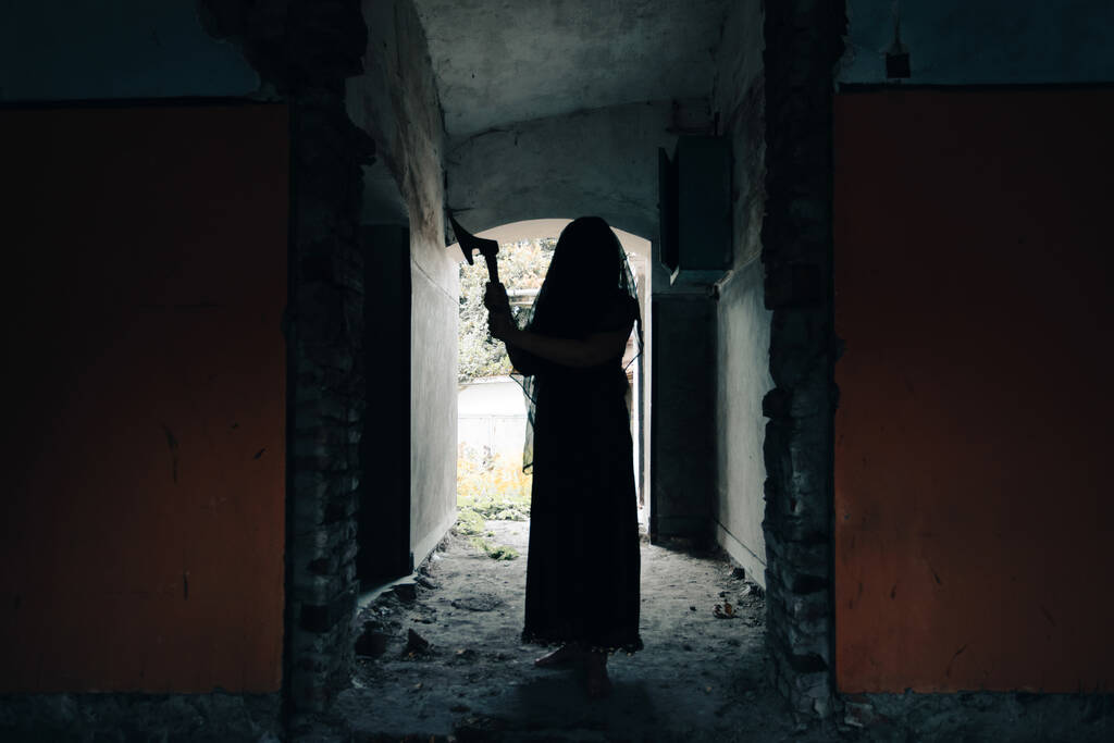 Ghost in abandoned, haunted house. Horror scene of spooky silhouette holding old axe, halloween concept. - Photo, Image