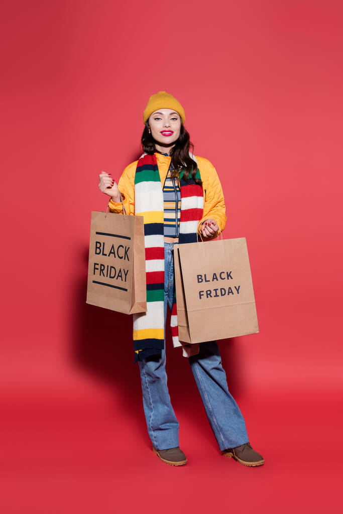 teljes hossza boldog nő sapka és sál gazdaság bevásárló táskák fekete péntek felirat piros  - Fotó, kép