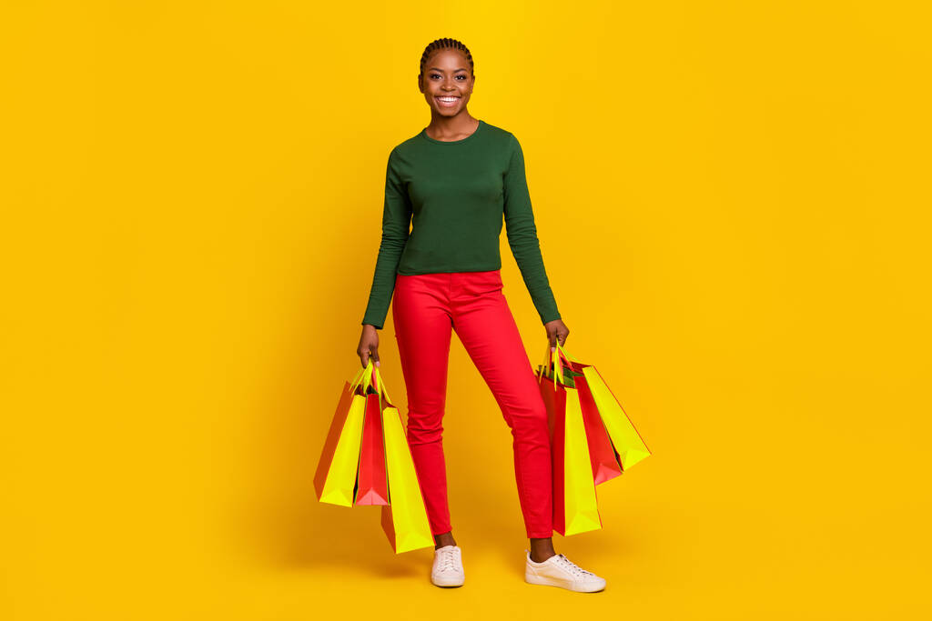 Volledige lengte foto van schattige lieve vrouw dragen groene shirt met shoppers geïsoleerde gele kleur achtergrond. - Foto, afbeelding