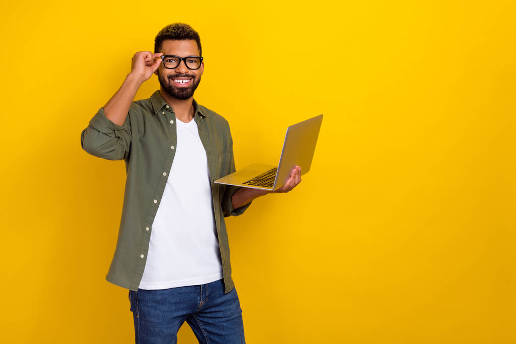 自信を持ってスマートマンの写真は、現代的なデバイスを書き込みカーキシャツの手の眼鏡を着用空のスペース孤立黄色の色の背景. - 写真・画像