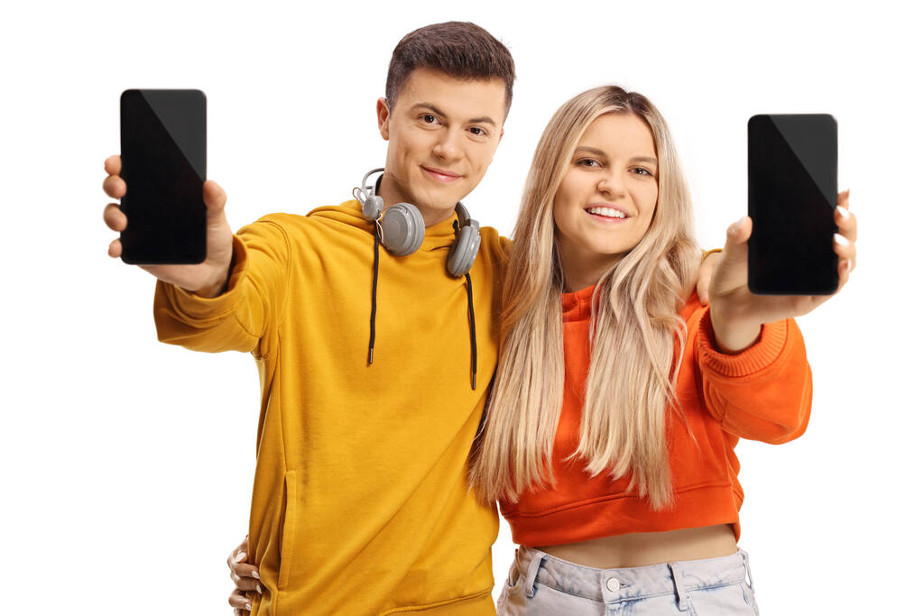 Adolescente maschio e femmina mostrando smartphone e sorridente isolato su sfondo bianco - Foto, immagini