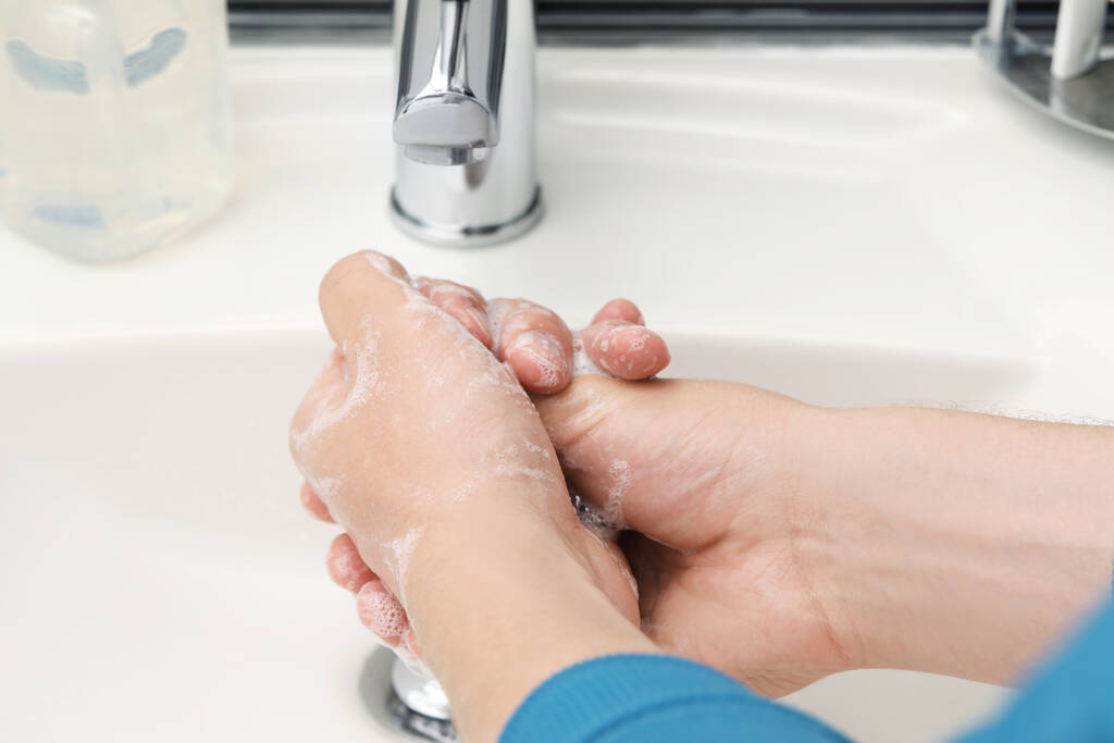 Uomo che si lava le mani con sapone sopra il lavandino in bagno, primo piano
 - Foto, immagini
