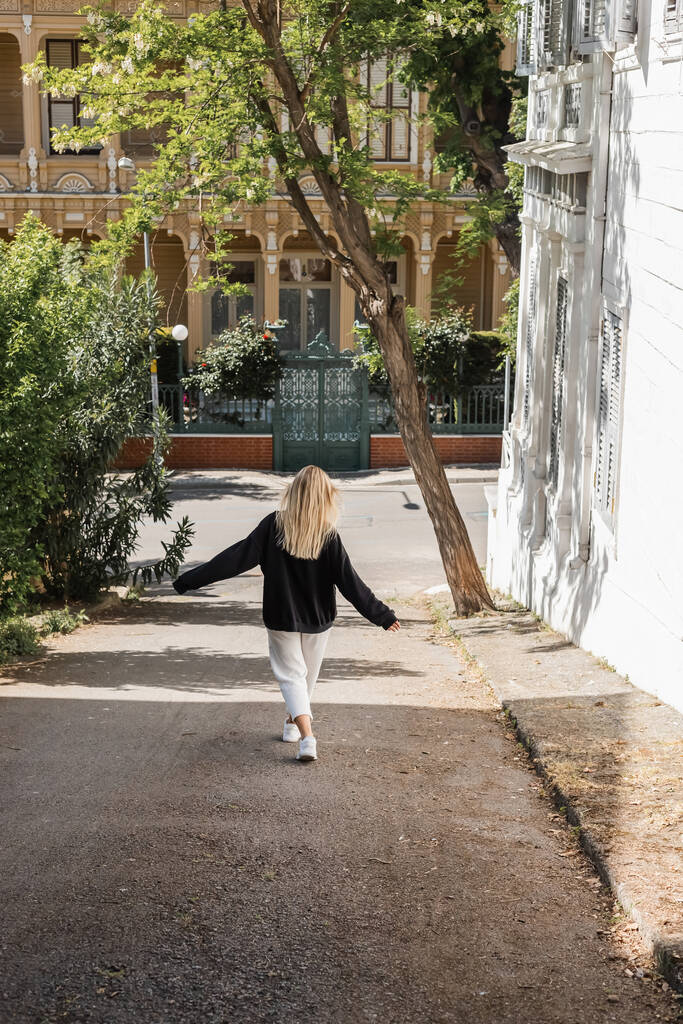 visão traseira da jovem mulher loira na roupa da moda andando na rua em peru  - Foto, Imagem