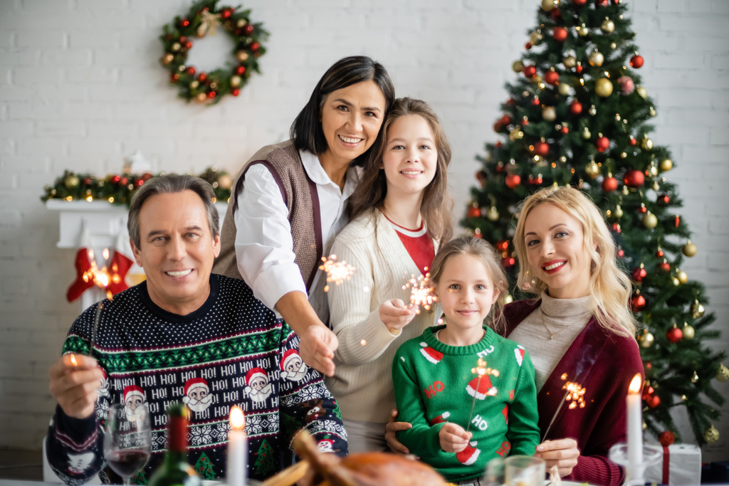 cheerful multiethnic family holding sparkles during christmas celebration - Photo, Image