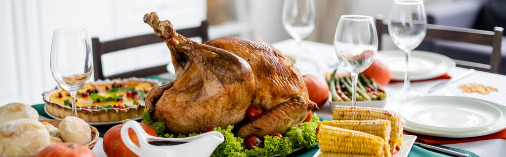 delicious roasted turkey near grilled corn and blurred pumpkin pie on table with thanksgiving dinner, banner - Photo, Image