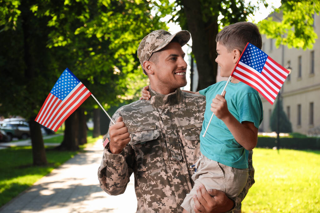 Soldat et son petit fils avec des drapeaux américains à l'extérieur. Journée des anciens combattants aux États-Unis - Photo, image