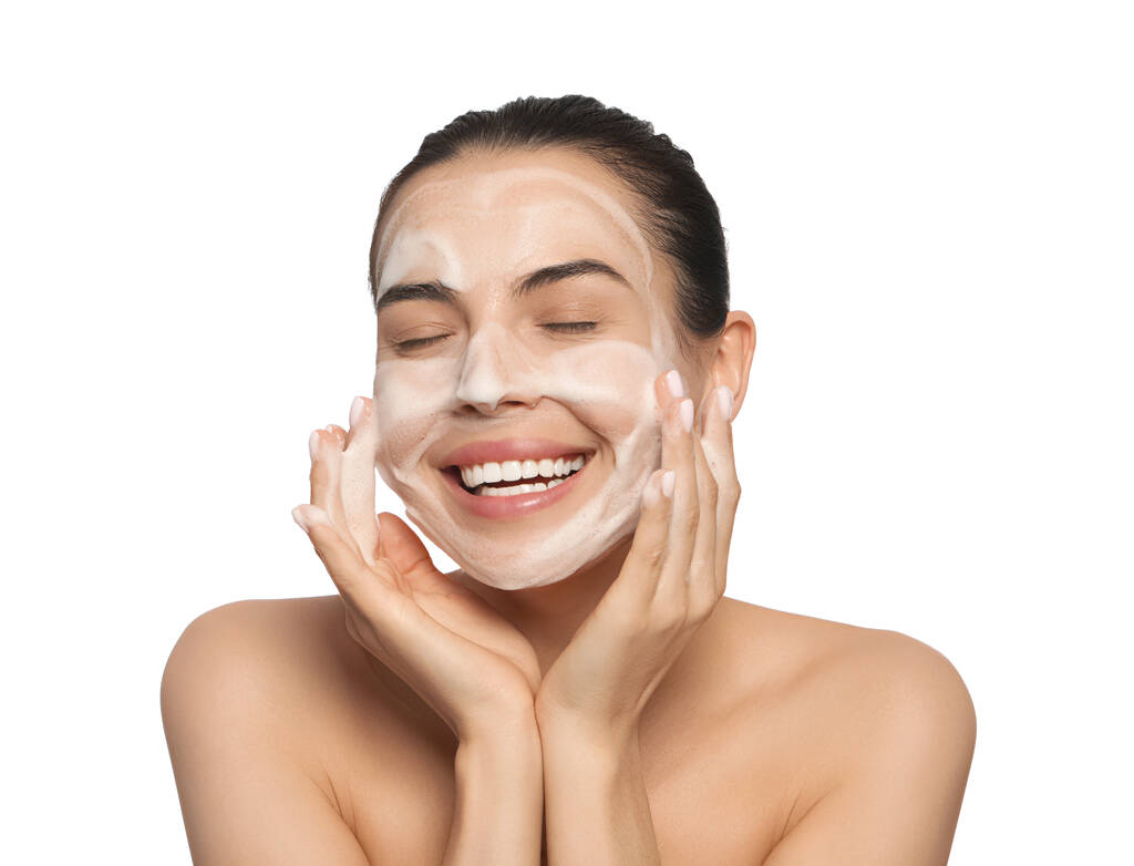 Szczęśliwa młoda kobieta myje twarz produktem kosmetycznym na białym tle - Zdjęcie, obraz