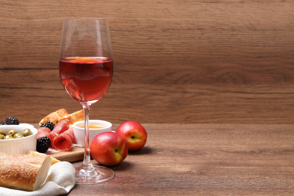 Un verre de délicieux vin de rose et des collations sur une table en bois. Espace pour le texte - Photo, image
