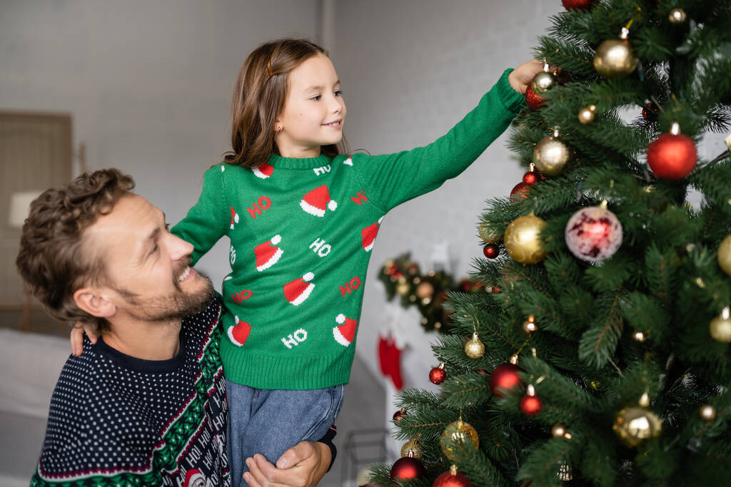 Père et fille positifs décorant l'arbre de Noël à la maison  - Photo, image