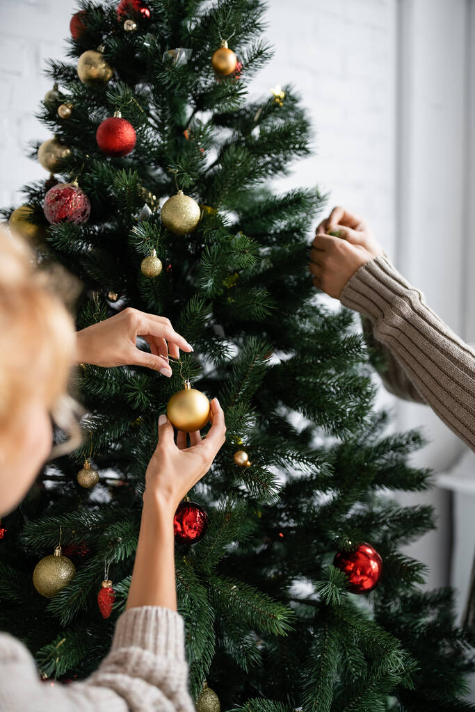 Donna sfocata decorazione albero di Natale con marito a casa  - Foto, immagini