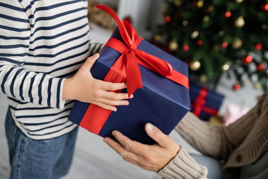 Vue recadrée de fille donnant cadeau à papa pendant la célébration de Noël à la maison  - Photo, image