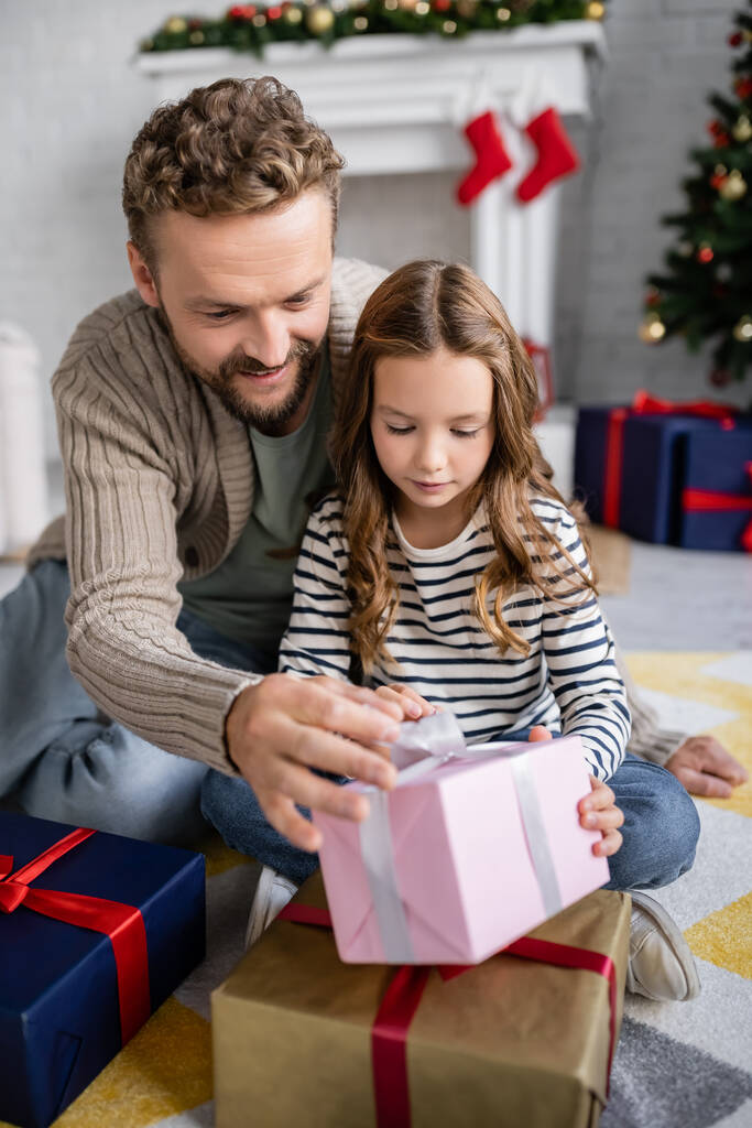 Positive man and daughter holding new year present at home  - Photo, Image