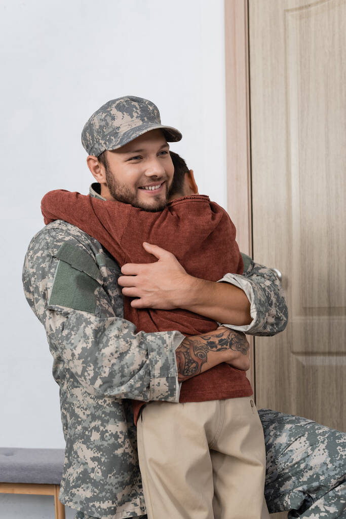 Vidám katona, aki magához öleli fiát, hogy otthon találkozzon vele. - Fotó, kép