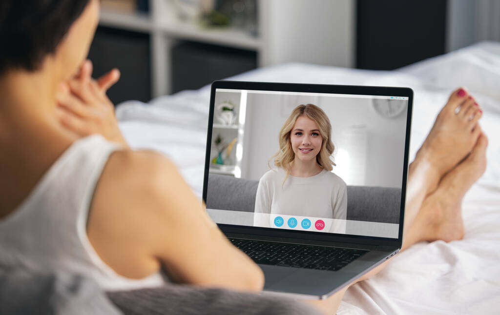 Happy mother sitting on bed having video call on laptop with young lady, her daughter. Pleasant morning conversation with cheerful girl at computer screen. Connection people concept - Photo, Image