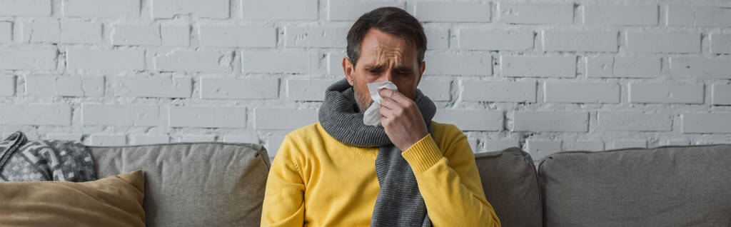 鼻水と紙のナプキンにくしゃみに苦しんで暖かいスカーフの病気の男、バナー - 写真・画像
